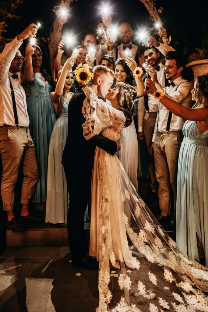 bride and groom kissing with guests surrounding them with phones