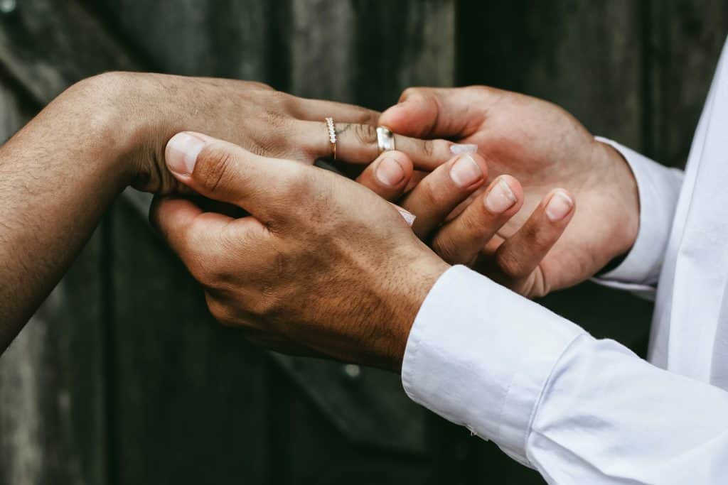 a close up photo of two hands with wedding rings