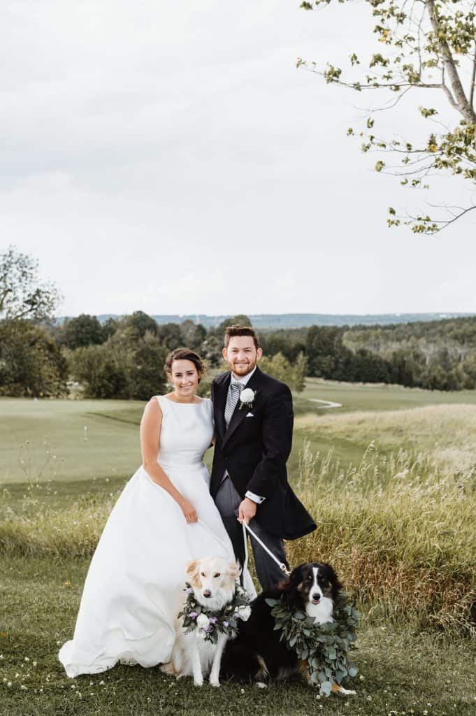 bride and groom with their two dogs dressed up in bouquet collars