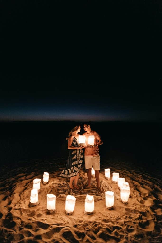 couple on a beach at night holding paper lanterns