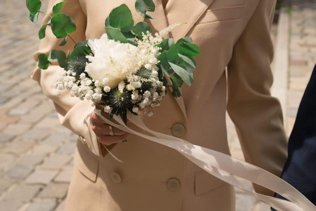 photo of a bride in a tan suit holding a bouquet