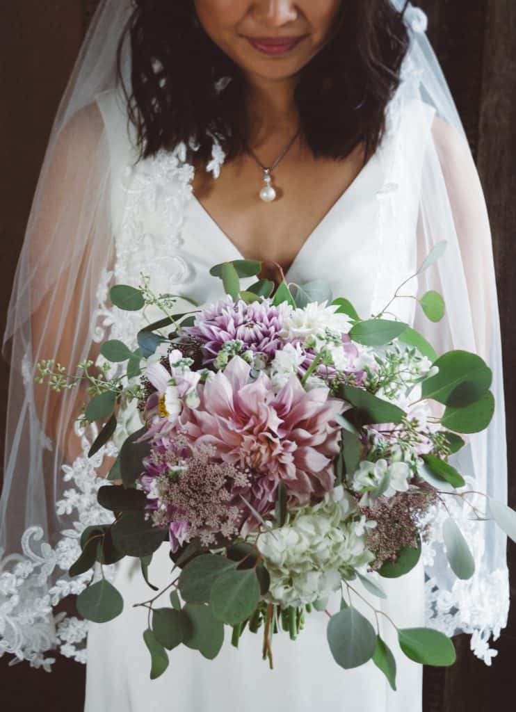 indian bride in a white dress holding a bouquet