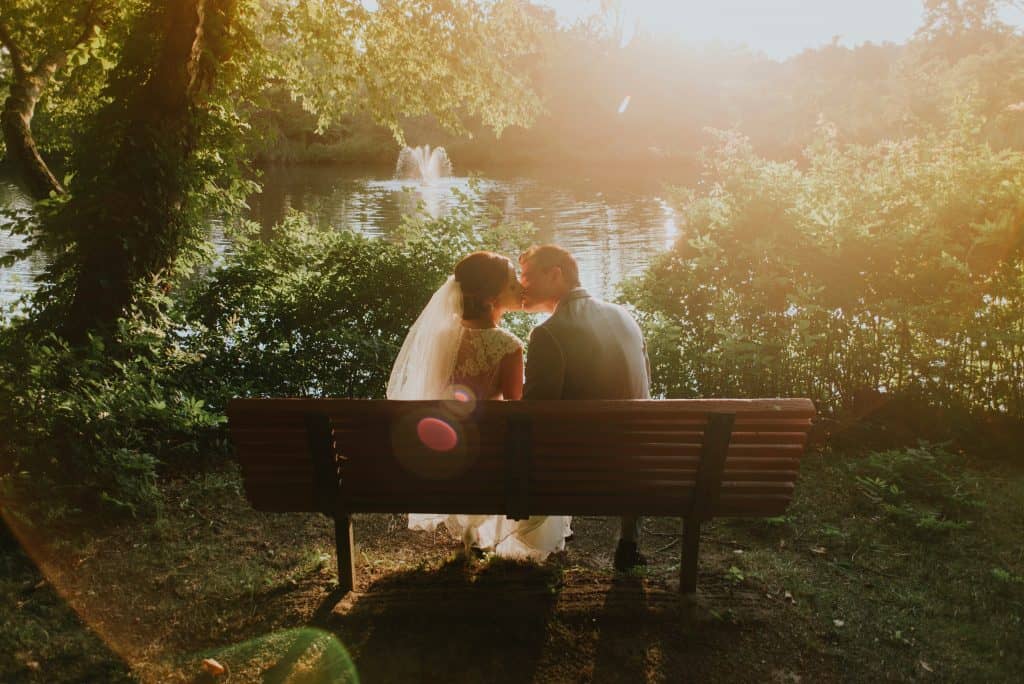 sunday wedding in the park - couple kissing on a bench
