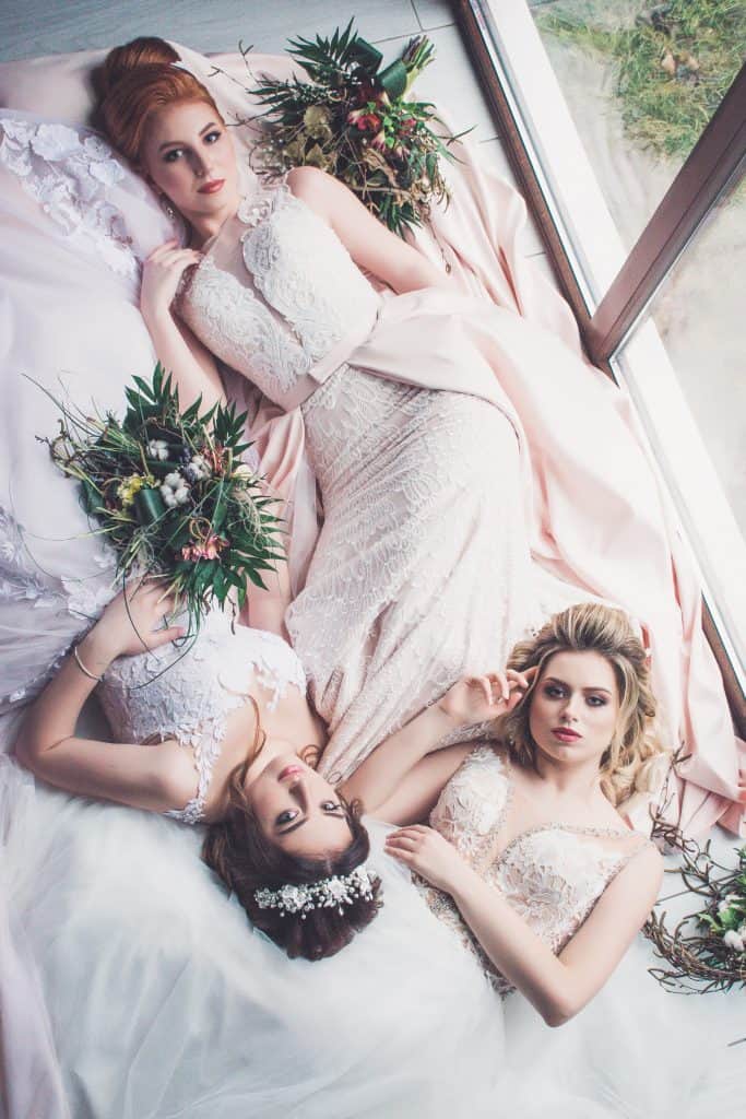 three brides in wedding dresses laying on the floor
