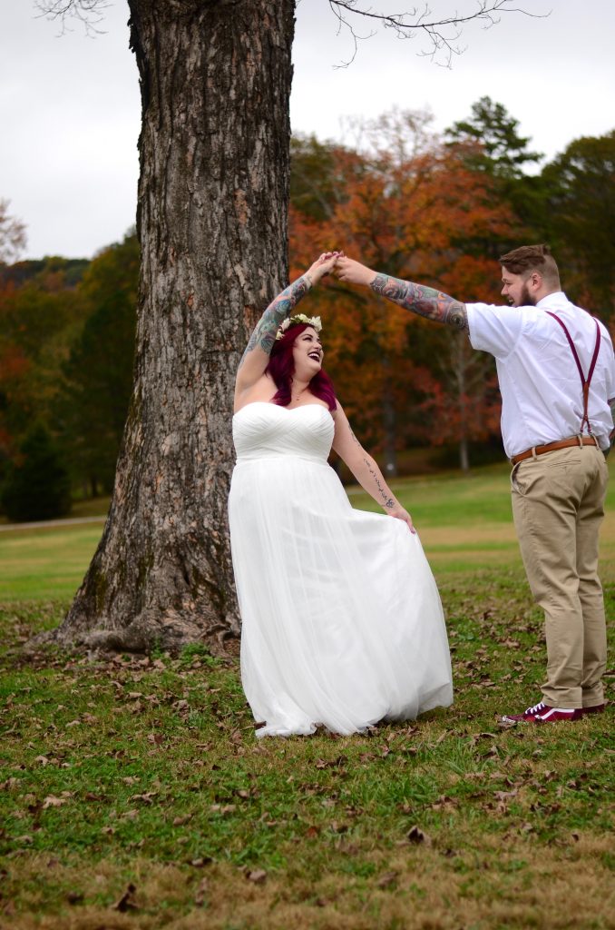 photo of a bride being twirled by a groom in the park