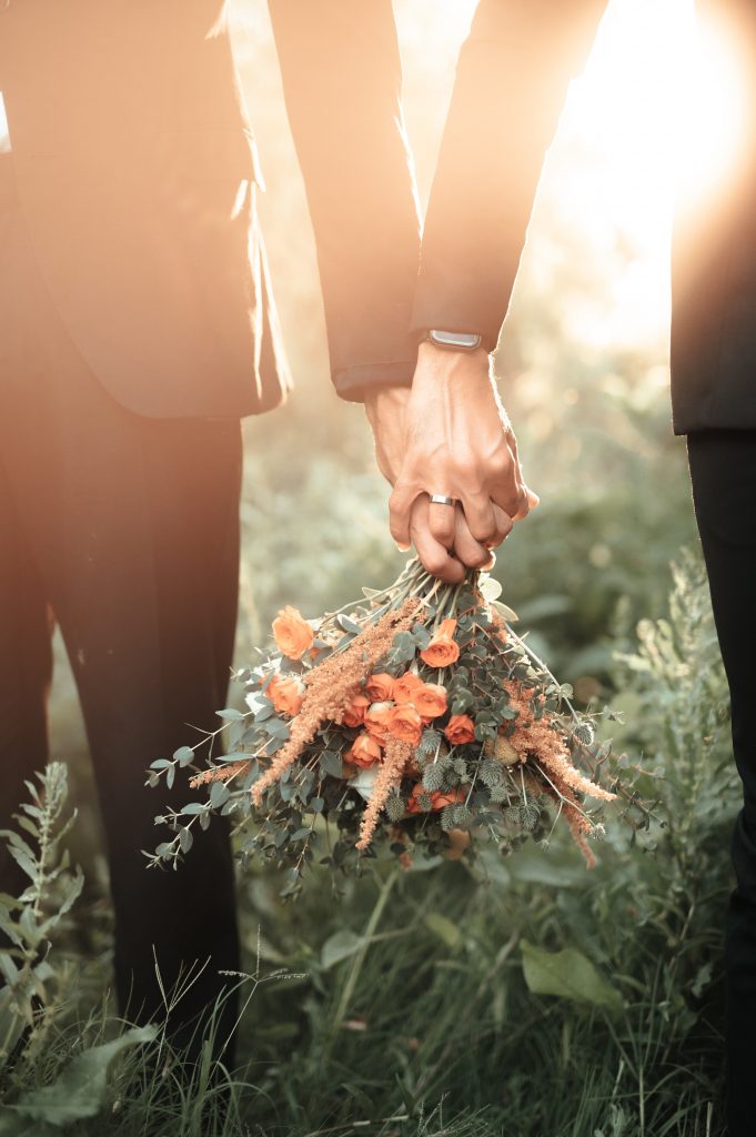 photo of two grooms holding a bouquet and holding hands