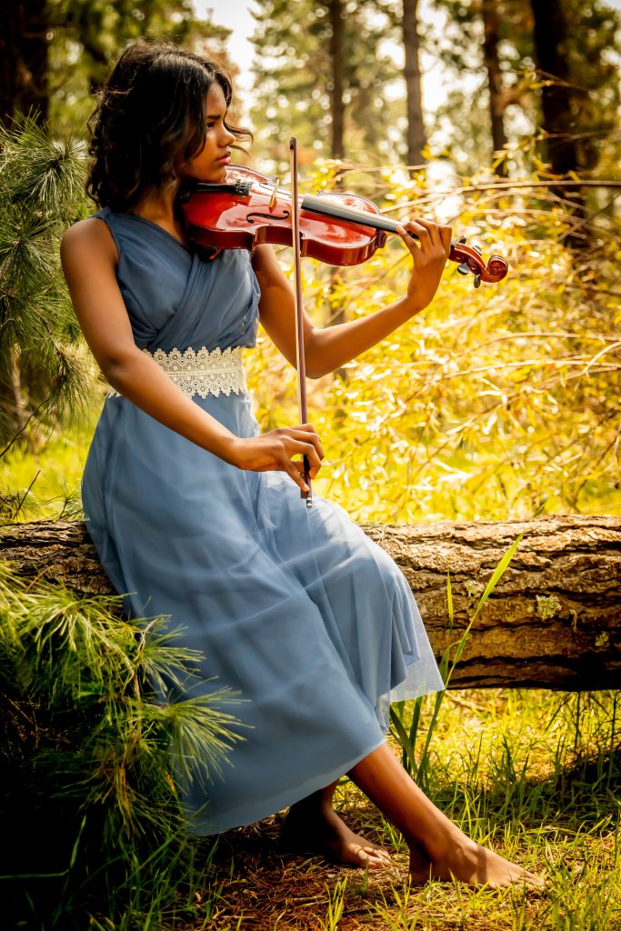 violinist playing in a blue dress in the grass