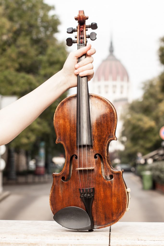 Person holding a violin in front of a capital building