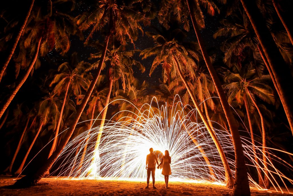 photo of a bride and groom with palm trees and a fireworks display
