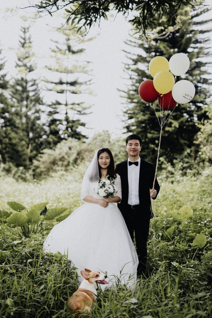 bride and groom with balloons and a corgi