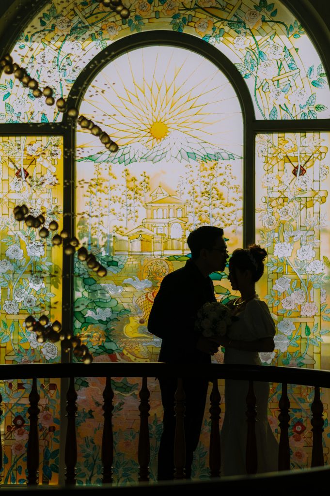 bride and groom in front of a stained glass window