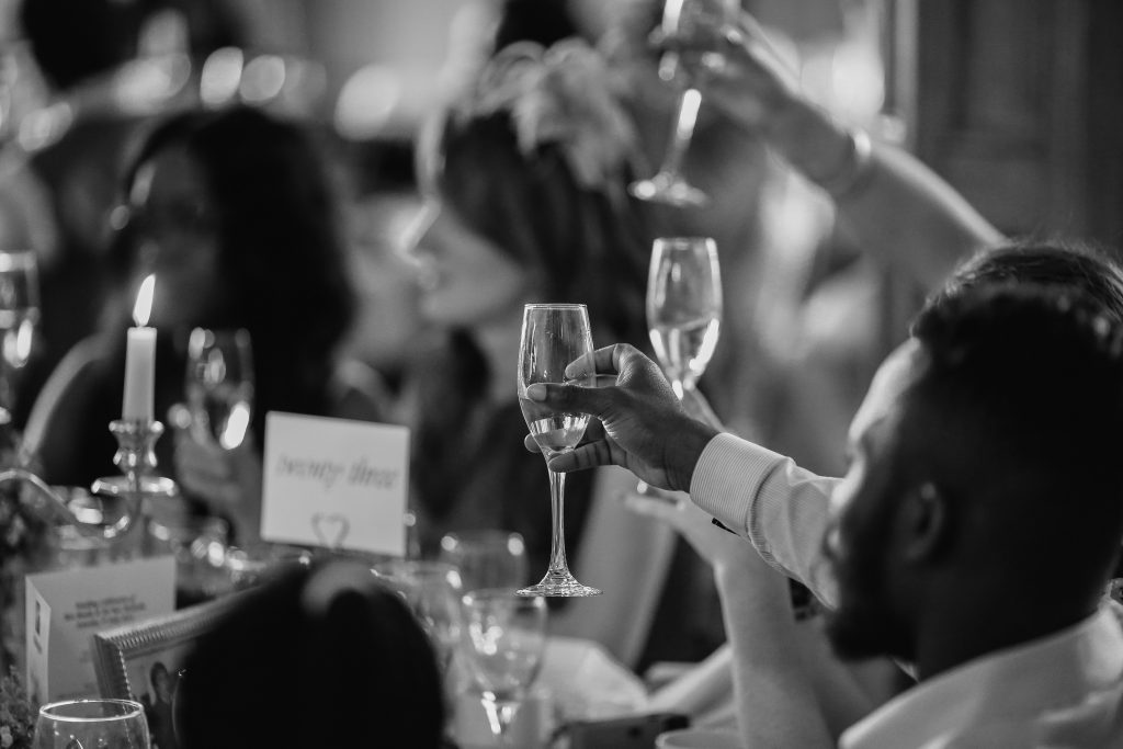 black and white photo of wedding guests toasting the bride and groom