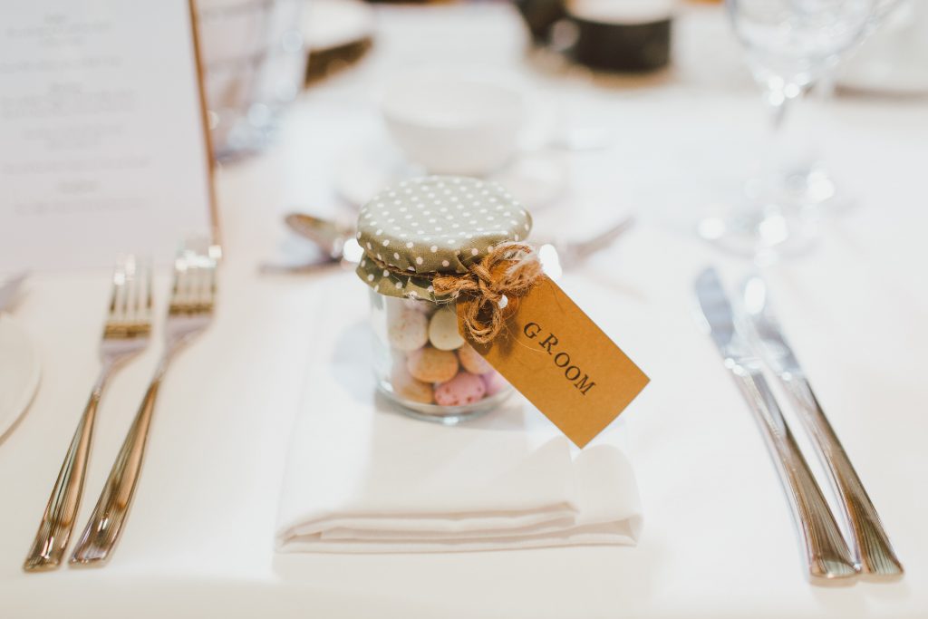 table and white table cloth with a jar filled with candy and tag that says "groom"