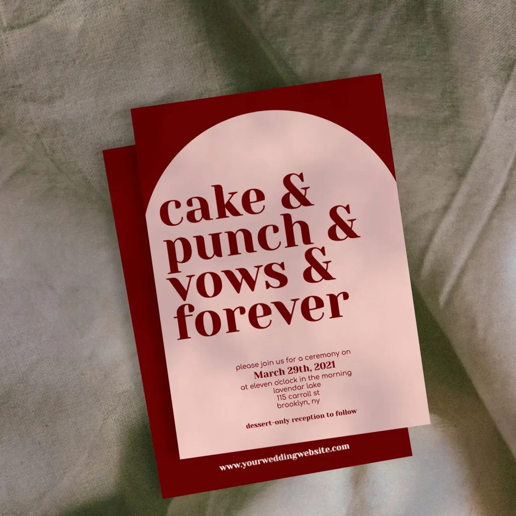 cake and punch arch wedding invitation in blush and burgundy on a grey sheet backgroun