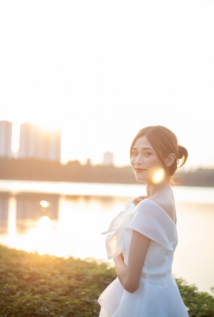 bride looking into the camera at sunset standing in front of water and city skyline