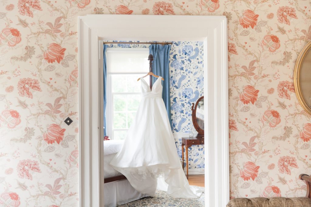 wedding dress hung up in a room with blue and white wallpaper