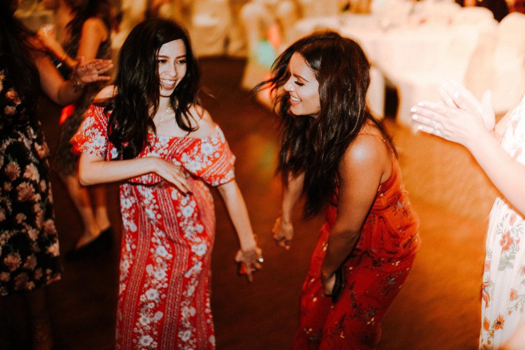 two female wedding guests dancing wearing red dresses