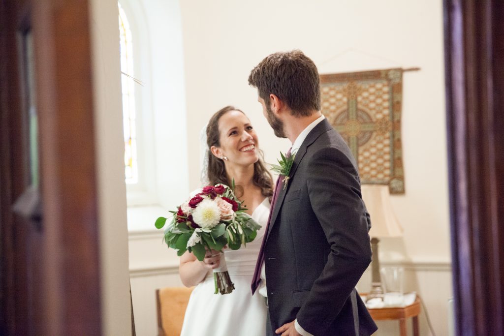 bride holding a bouquet looking at a groom in a church