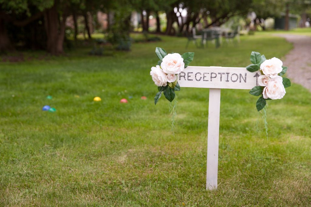white reception sign with fake pink flowers